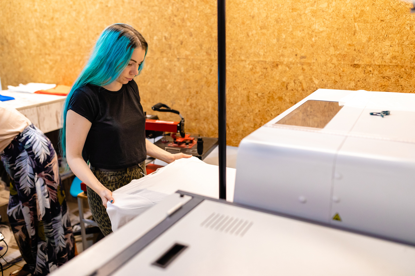 In digital printing workshop female worker preparing T-shirt for printing